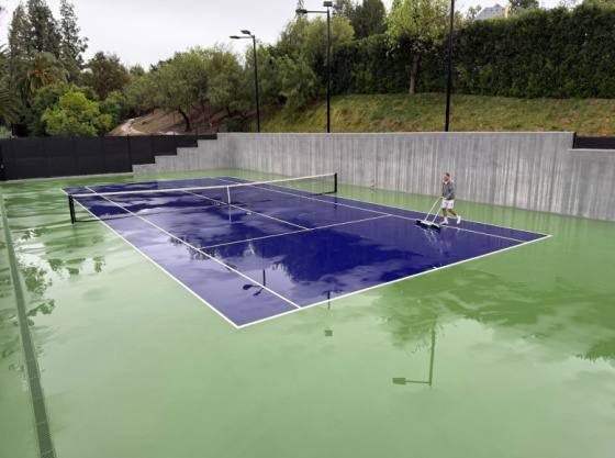 Squeegeeing water off the court after a rainstorm