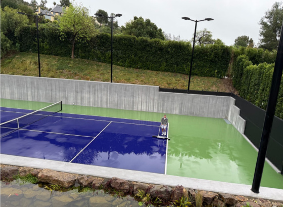 Squeegeeing water off the court after a rainstorm